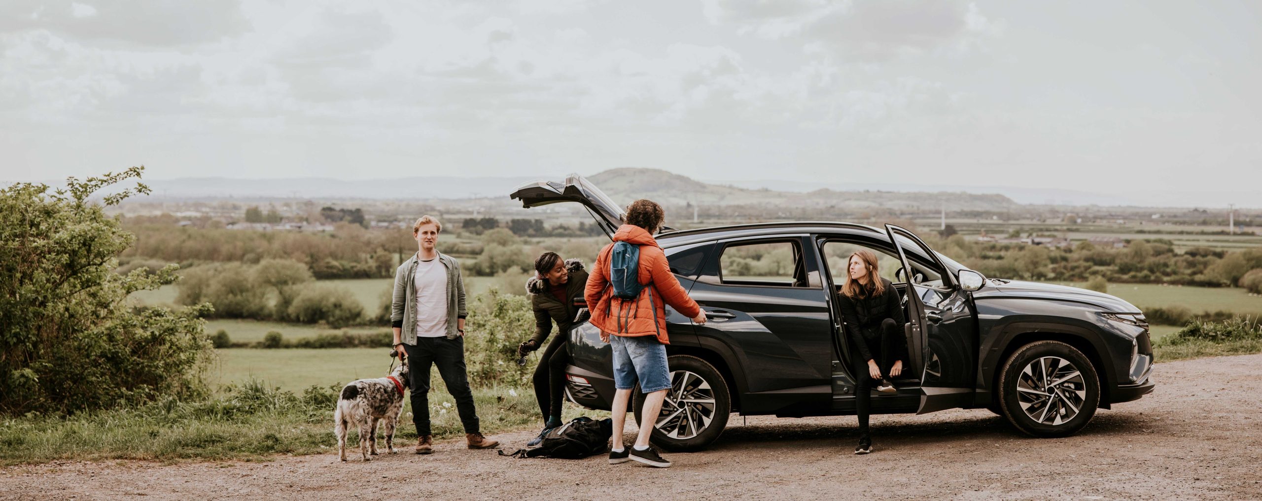 group of friends in front of a car during fall